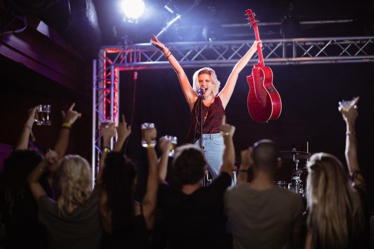 Female performer with arms raised singing during music event